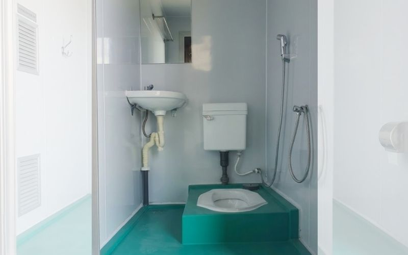 Nội thất bên trong bốt vệ sinh di động composite gồm bồn cầu bệt, lavabo và quạt thông gió